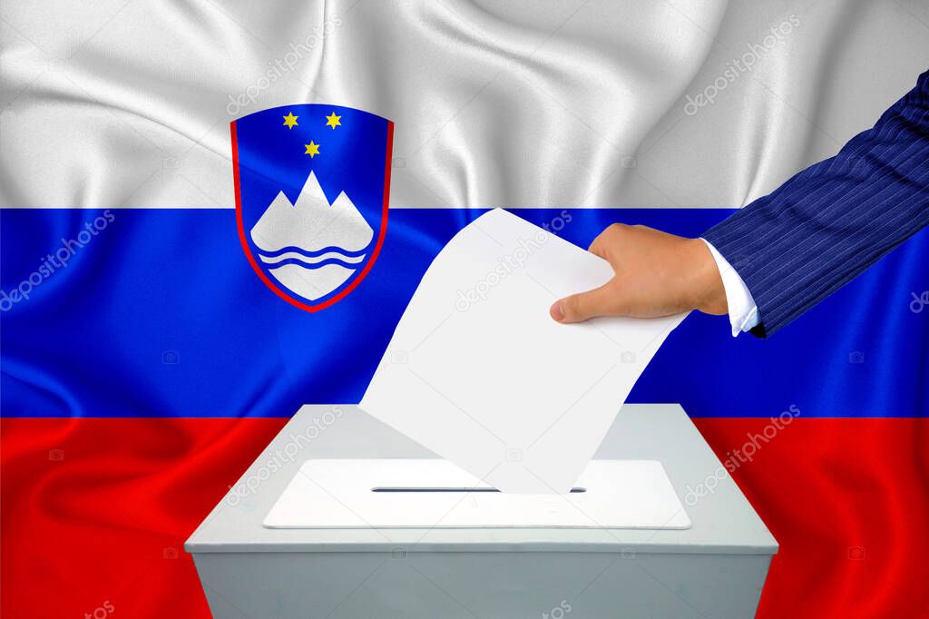 Elections in the country - voting at the ballot box. A man's hand puts his vote into the ballot box. Flag Slovenia on background.