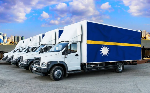 Nauru flag on the back of Five new white trucks against the backdrop of the river and the city. Truck, transport, freight transport. Freight and Logistics Concept