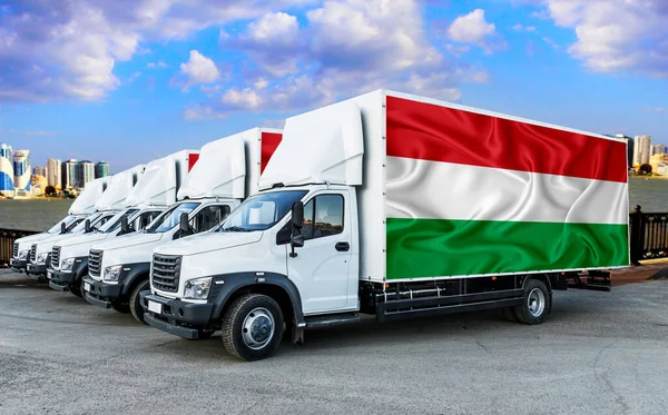 Hungary flag on the back of Five new white trucks against the backdrop of the river and the city. Truck, transport, freight transport. Freight and Logistics Concept