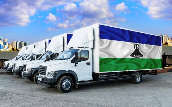 lesotho flag on the back of Five new white trucks against the backdrop of the river and the city. Truck, transport, freight transport. Freight and Logistics Concept