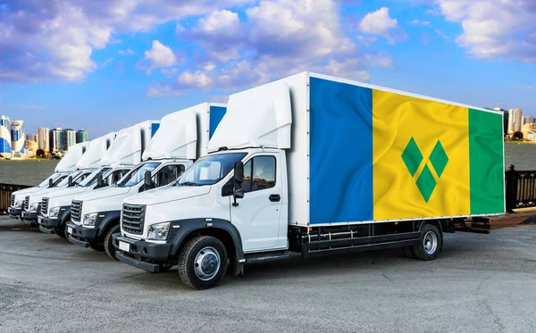 Saint Vincent and the Grenadines flag on the back of Five new white trucks against the backdrop of the river and the city. Truck, transport, freight transport. Freight and Logistics Concept