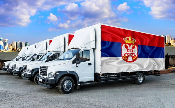 Serbian flag on the back of Five new white trucks against the backdrop of the river and the city. Truck, transport, freight transport. Freight and Logistics Concept