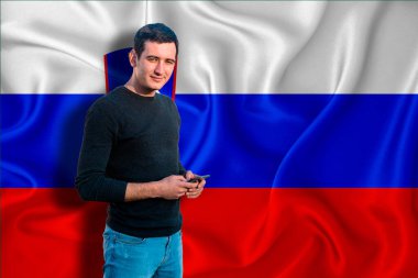 Arkaplanda Slovenya bayrağı var. Genç adam gülümsüyor ve elinde bir akıllı telefon tutuyor. Tasarım çözümleri kavramı.
