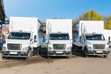 Kalkışa hazır üç yeni beyaz kamyon park halinde. Malların konsept bir şekilde teslimi veya sevkiyatı.