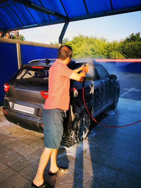 車の中で若い男が高圧下で車を洗う 選択的焦点 — ストック写真