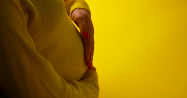 Торкаючись вагітного живота на жовтому фоні — стокове відео