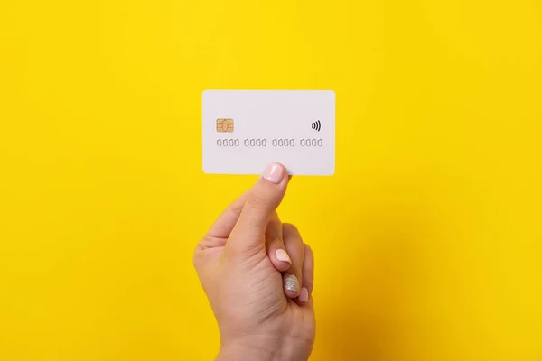 credit card in hand, card with electronic chip over yellow background