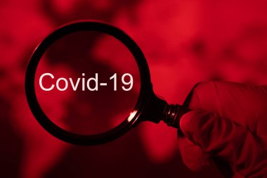 Büyüteç ve koronavirüs, kırmızı tonlu dünya haritası, kavram covid-19