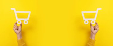 Sarı arkaplan üzerindeki alışveriş arabası sembolü, panoramik görüntü