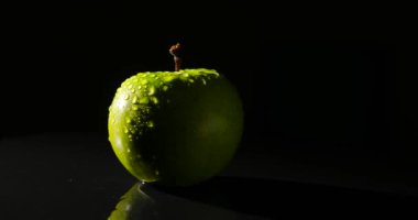 Siyah bir arkaplanda dönen yeşil bir elma