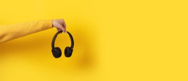 Sarı arkaplanda siyah kulaklıklar, panoramik görüntü