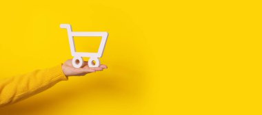Sarı arkaplan üzerinde alışveriş arabası, metin için yeri olan panoramik maket