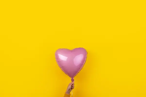 Różowy Balon Foliowy Kształcie Serca Dłoni Nad Żółtym Tle Szczęśliwy — Zdjęcie stockowe