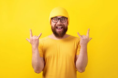 Komik adam sarı arka planda rock 'n roll hareketi yapıyor.