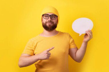 Beyaz adam sarı arkaplan üzerinde metin için boş alanı olan konuşma baloncuğu tutuyor