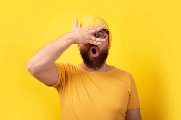 Impactado Hombre Mirando Través Los Dedos Sobre Fondo Amarillo —  Fotos de Stock