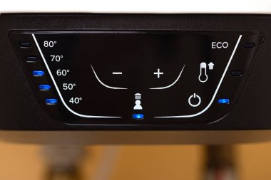 Ekolojik mod için ısı ayarları, sembolleri ve LED göstergeleri olan dijital bir su ısıtıcı kontrol panelinin yakın çekimini yapın. Çağdaş ve kullanıcı dostu arayüz.
