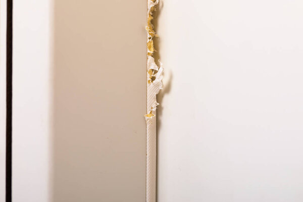 Крупный план поврежденной дверной рамы с обломками краски и видимой древесины, установленной на ровном фоне для ремонта или реконструкции.