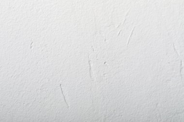 Temiz beyaz desenli bir duvara yakın plan, ince desenler ve kusurlar, arka plan veya tasarım modelleri için ideal.