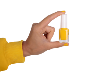 Şeffaf üzerinde sarı tırnak cilası tutan bir elin yakın çekimi. Güzellik, kozmetik ve manikür temaları için parlak, modern konsept.