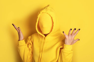 Sarı eşofmanlı, sarı tişörtlü, sarı arka planda duran, el kaldıran, modern ve cesur görsel konsept..