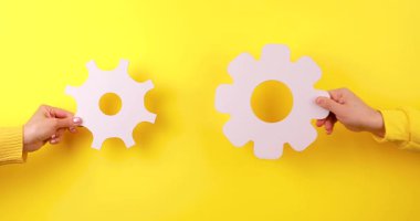 İnsan ellerinin birbirine kenetlenmiş vitesleri ayarlaması, kurulumu, onarımı, bakımı ve mühendislik süreçlerini sembolize etmesi. Takım çalışmasını temsil eden kavramsal 4K video,