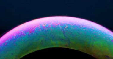 4K 'lık bir videoda zarif bir şekilde yüzen renkli sabun köpüğü göz kamaştırıcı parlak renkler ve sürekli değişen renk yansımaları sergiliyor..