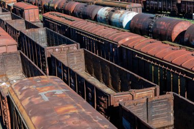 Demiryolu raylarındaki paslı yük vagonlarının hava görüntüsü, günışığı altında endüstriyel bozulma ve klasik dokuları gösteriyor..