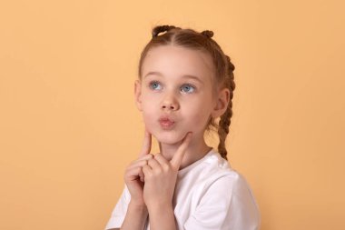 Beyaz gömlekli, saçları örgülü genç bir kızın portresi. Saf sarı bir arkaplanda düşünceli bir şekilde poz veriyor..