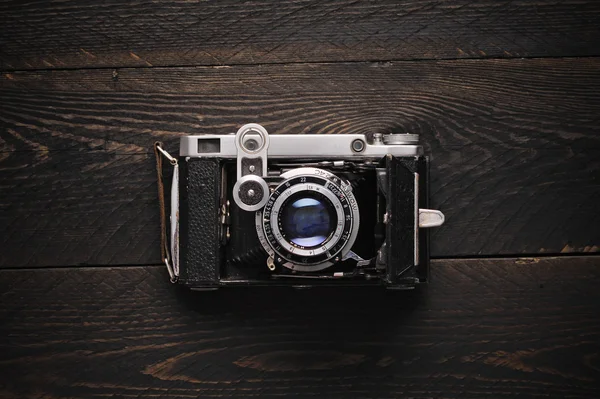 vintage old photographic field film sing lens camera on a darkness wooden background