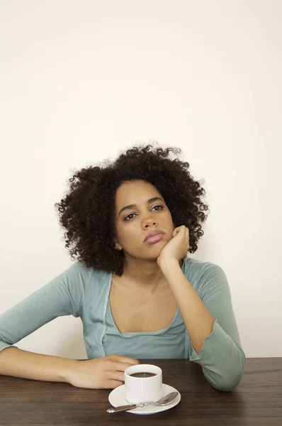 Mujer joven y rizada sentada a la mesa — Foto de Stock