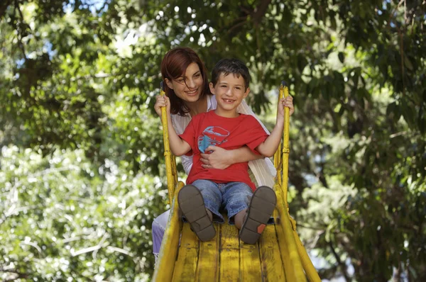 Mutter und Sohn auf der gelben Rutsche — Stockfoto