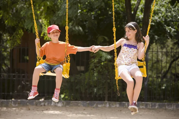 Small boy and girl swinging — Stock Photo, Image