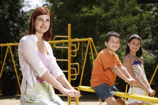 Mãe e crianças no parque infantil — Fotografia de Stock