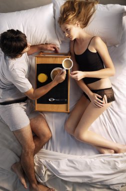 Çift yatakta kahvaltı yapıyor.