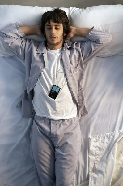 Young man listening music in bed — Stock Photo, Image