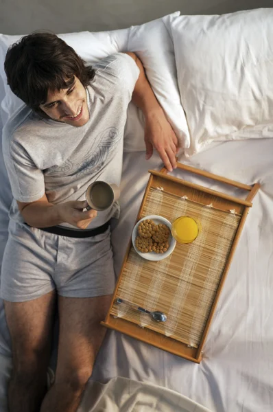 Mężczyzna jedzący śniadanie w łóżku — Zdjęcie stockowe