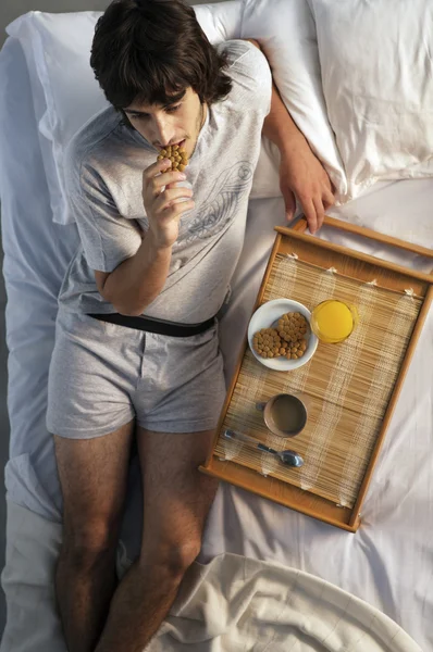 Homem tomando café da manhã na cama — Fotografia de Stock