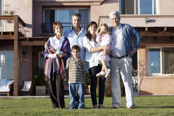 Familia de pie contra la casa grande — Foto de Stock