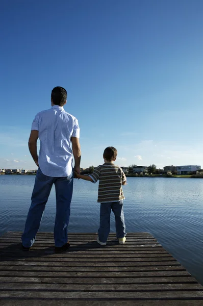 Father and son standing on wooden pier — Stock Photo, Image