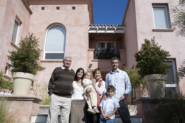 Family standing against big house — Stock Photo, Image