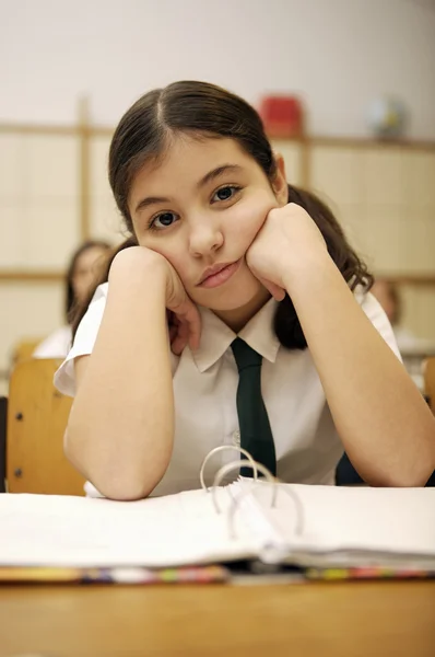 Verveeld schoolmeisje aan de balie — Stockfoto