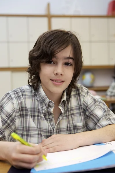 School jongen zitten door het Bureau — Stockfoto