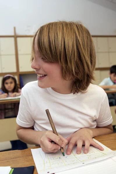 Skolan pojke sitter vid skrivbordet — Stockfoto