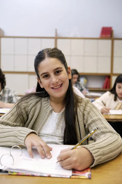 Escola menina sentada ao lado da mesa — Fotografia de Stock