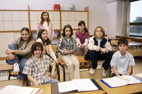 Crianças em idade escolar posando em sala de aula — Fotografia de Stock