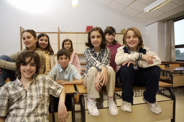 Crianças em idade escolar posando em sala de aula — Fotografia de Stock