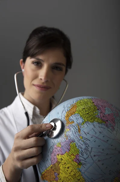 Doutor ouvindo globo com estetoscópio — Fotografia de Stock