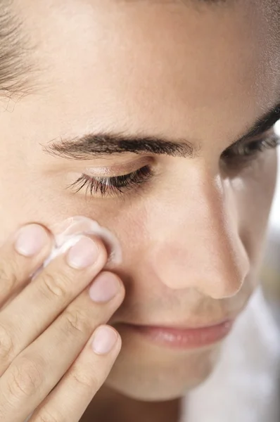 man applying lotion to his face