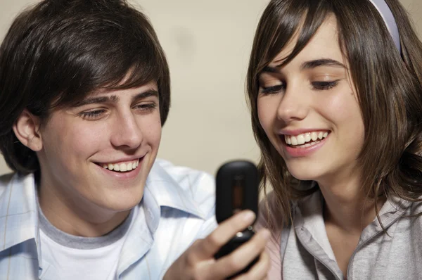 Tizenéves lány és egy fiú látszó telefon — Stock Fotó